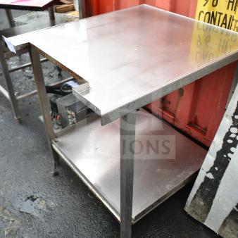 Stainless steel commercial table with under shelf, in used condition, featuring sturdy metal legs and a smooth surface.