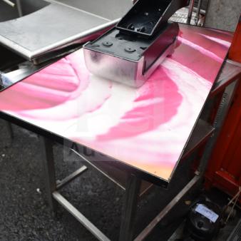 Commercial table with onion print top, featuring a small metal box. Sturdy frame, used condition.