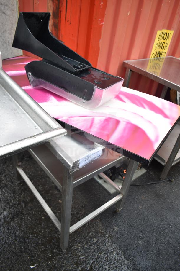 Commercial metal table with attached onion picture and a black plastic chute. Condition shows outdoor exposure.