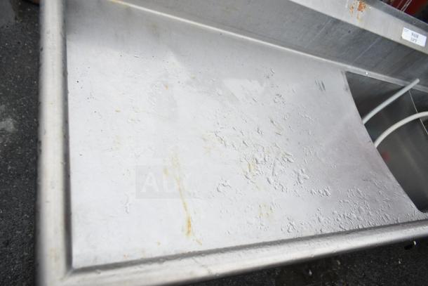 Commercial 3 bay sink with dual drain boards, stainless steel, visible wear, label reads "WASH 110°F," showing industrial use.