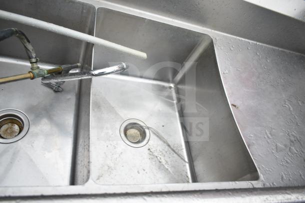 Commercial 3 bay sink with dual drain boards, stainless steel, visible faucet attachments, light wear, suitable for restaurant use.