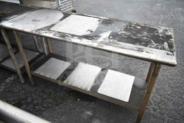 Commercial stainless steel table with under shelf, used condition, visible surface wear and marks, ideal for kitchen use.