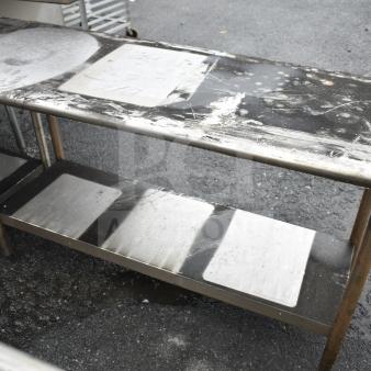 Commercial stainless steel table with under shelf, used condition, visible surface wear and marks, ideal for kitchen use.