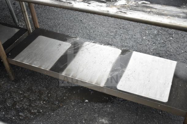 Commercial metal table with undershelf, showing wear and scuffs, suitable for kitchen or industrial use.