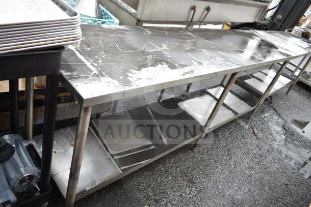 Commercial stainless steel table with under shelf, showing signs of wear, sturdy metal construction, ideal for kitchen use.