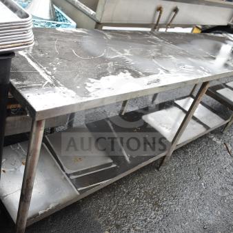 Commercial stainless steel table with under shelf, showing signs of wear, sturdy metal construction, ideal for kitchen use.