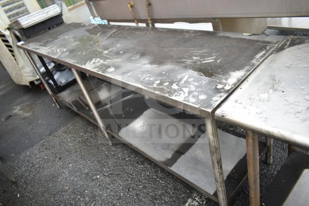 Commercial stainless steel table with under shelf, visible wear, suitable for kitchens or industrial use.