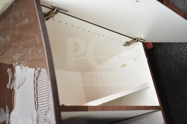 Counter with trash deposit hole, featuring two open doors. Visible hinges, white interior with slight discoloration.