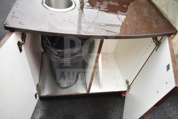 Counter with trash deposit hole and two doors, featuring an internal trash bin. Top surface is brown with water droplets.