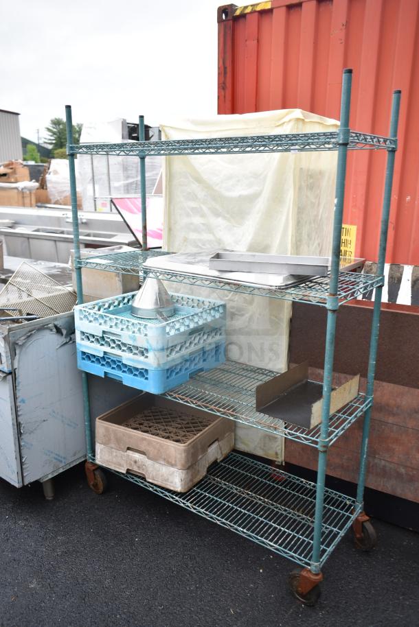 Green 4-tier wire shelving unit on casters, includes contents. Buyer must dismantle. Ideal for commercial use.