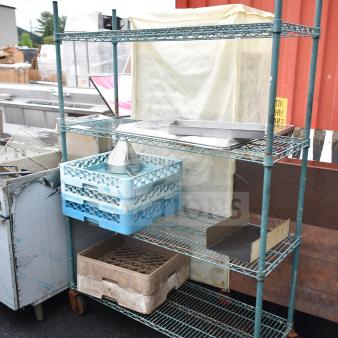 Green 4-tier wire shelving unit on casters, includes contents. Buyer must dismantle. Ideal for commercial use.