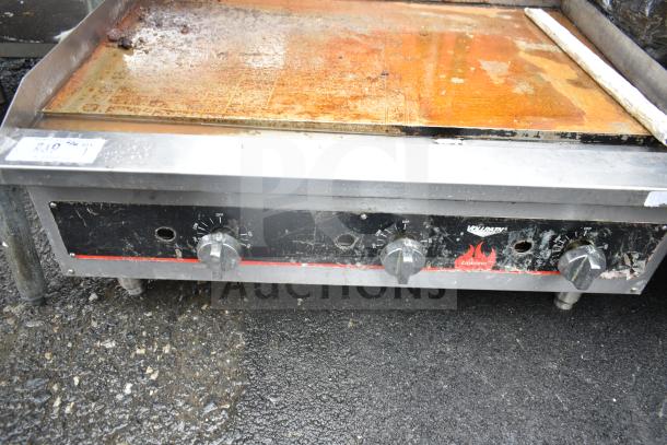 Vollrath Cayenne commercial gas griddle with thermostatic controls, worn surface, visible knobs, sturdy metal build.