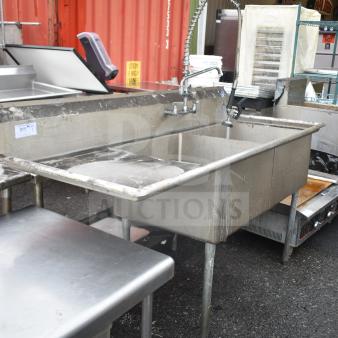 Commercial 2-bay sink with left-side drain board, durable metal finish, integrated sprayer, and faucet. Good condition.