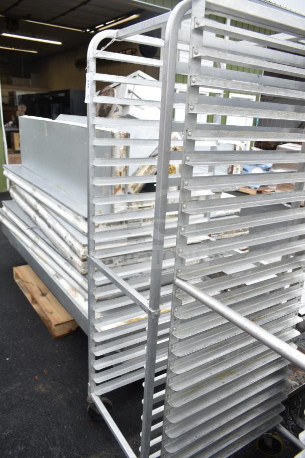 Commercial pan transport rack with multiple tiers, on sturdy commercial casters, shown outdoors; used condition.