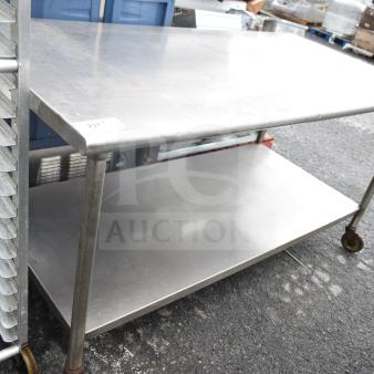 Commercial table with under shelf on casters, stainless steel, used condition, ideal for kitchen or workshop use.