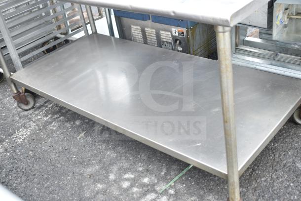Commercial table with under shelf, stainless steel, on industrial casters. Some wear visible. Ideal for heavy-duty use.