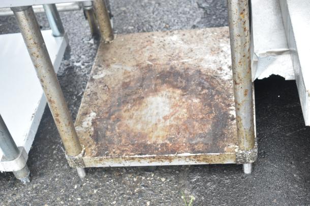Commercial equipment stand with under shelf, rusted metal, sturdy legs, used condition, ideal for industrial use.
