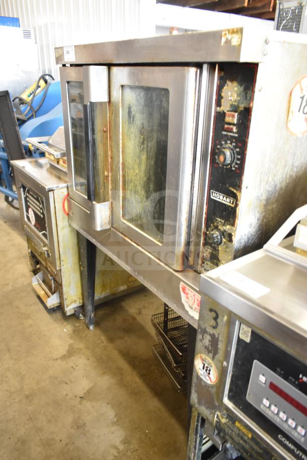 Hobart commercial full-size convection oven with view-through doors, thermostatic controls, and metal legs. Moderate wear visible.