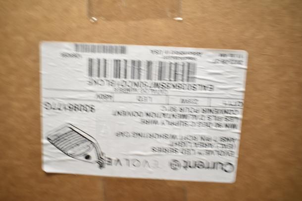 Box containing 4 Current Evolve LED Flood Lights, new with original packaging. Label includes barcode and product details.