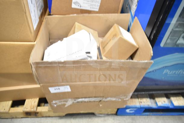 Cardboard box with 16 assorted items including LED emergency light battery backup, DualLite double remote heads, and exit signs.