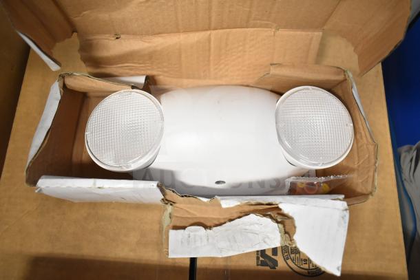 Cardboard box containing a DualLite dual remote head emergency light, showcasing the LED heads, in opened packaging.