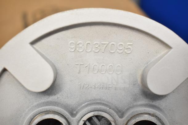 Close-up of a metal component with engravings "93037095," "T10000," and "1/2-14NPT," part of auction lot including LED lights and DualLite items.