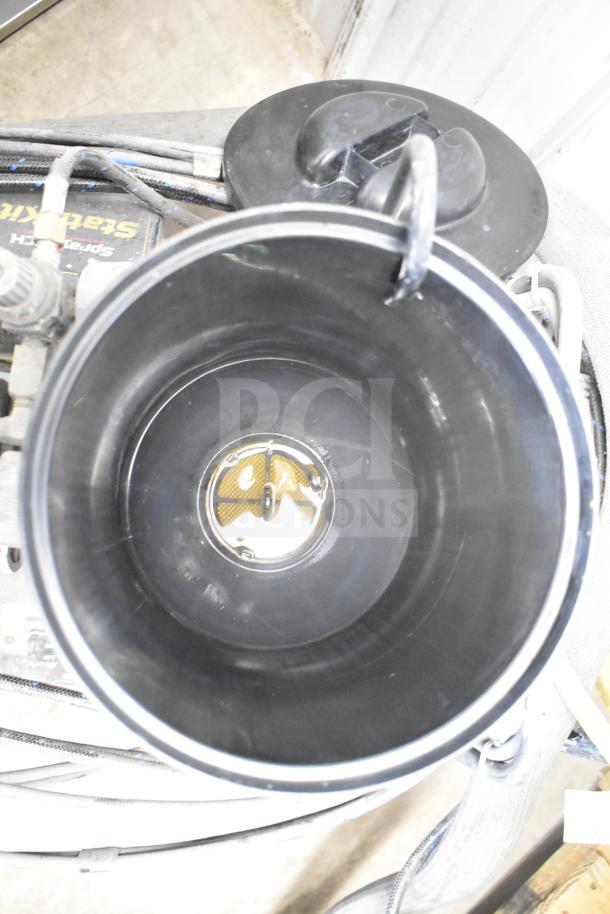 CapSpray Compressor/Pump with visible hoses and connections. Black container with secure lid. Appears in used condition.