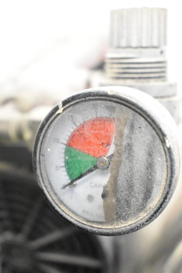 CapSpray Compressor/Pump with pressure gauge; shows signs of wear; gauge dial marked with green and red zones.