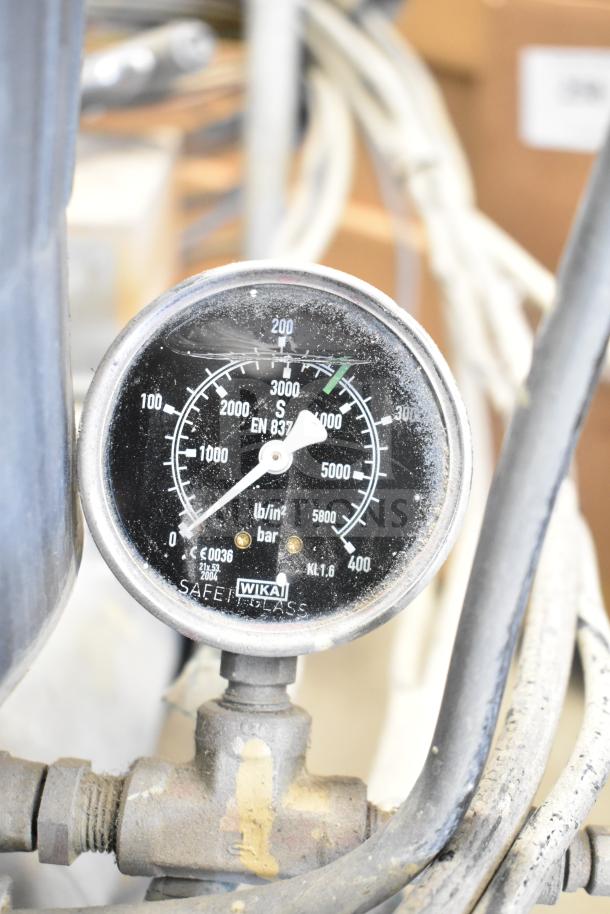 SprayTech 1075 Airless Spraying System pressure gauge, displaying 0-6000 psi and 0-400 bar, with visible wear.