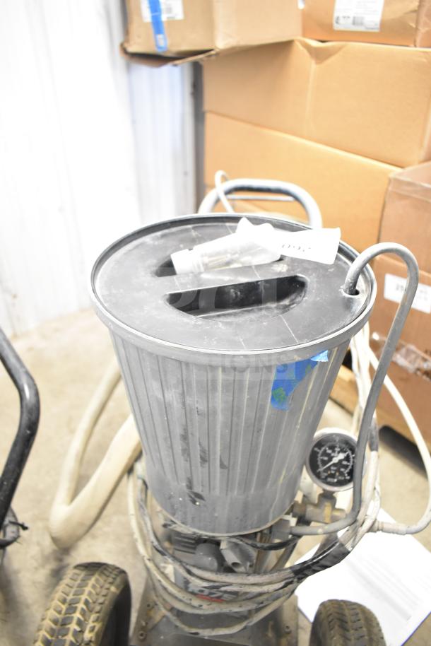 SprayTech 1075 Airless Spraying System in used condition with metal canister, hose attachment, and pressure gauge.