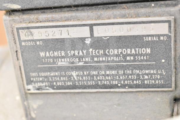 Close-up of the label on a Wagner SprayTech 1075 Airless Spraying System. The label shows model number 0295271 and serial number E0500393, indicating its production details. The label includes patent numbers, suggesting proprietary technology. The item appears to be used.