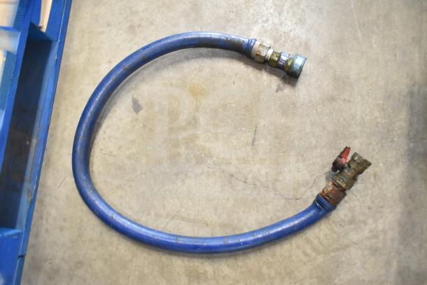 Blue hose with metal fittings, appears worn, possibly used for gas or fluid transfer. No identifiable tags or labels.