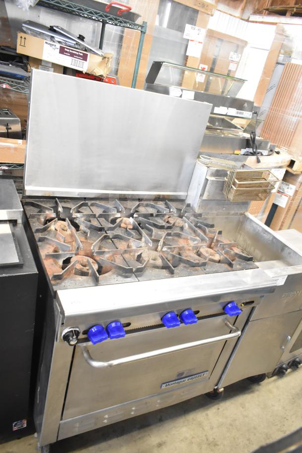 Montague Grizzly 6 burner commercial gas range with oven and backsplash. Features blue knobs and sturdy construction.