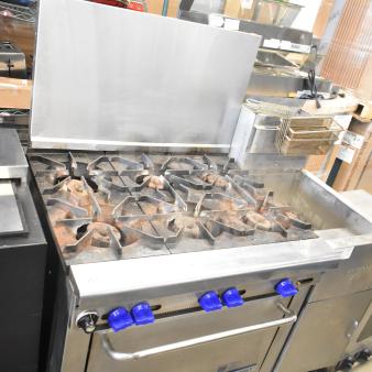 Montague Grizzly 6 burner commercial gas range with oven and backsplash. Features blue knobs and sturdy construction.