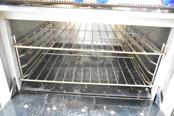 Montague Grizzly commercial oven interior with racks, clean condition, part of a 6 burner gas range with backsplash.