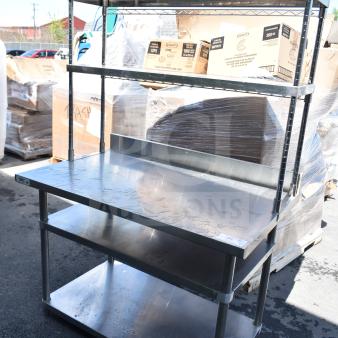 Stainless steel table with 2 under shelves and 2-tier over shelf. Seen outdoors, in good condition. Ideal for kitchen use.