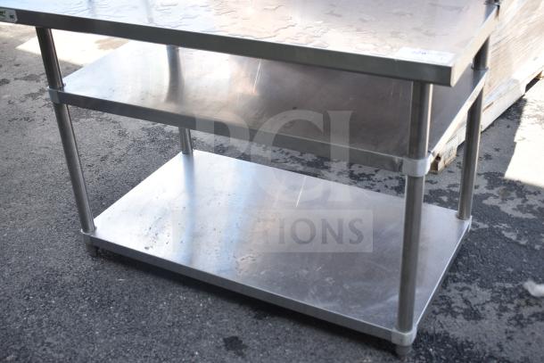 Stainless steel table with two under shelves and two-tier over shelf, sturdy construction, and used condition. Ideal for storage.