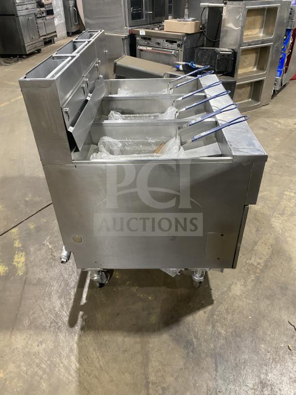 Pitco SG14-JS stainless steel triple-bay deep fat fryer system, on casters, with digital controls, basket hanger, and backsplash.