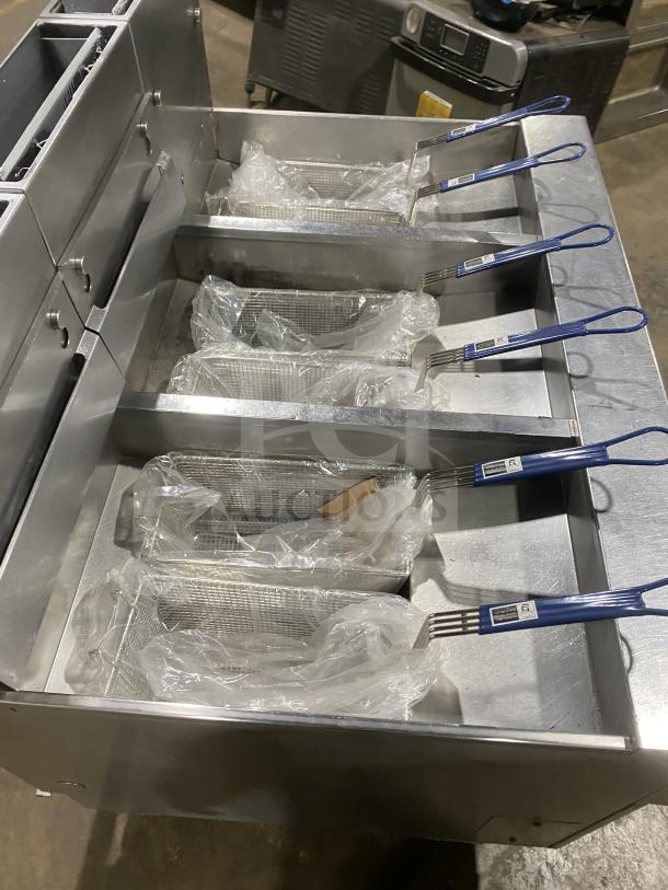 Pitco SG14-JS stainless steel triple-bay fryer with digital controls, fryer baskets, and basket hanger on casters.