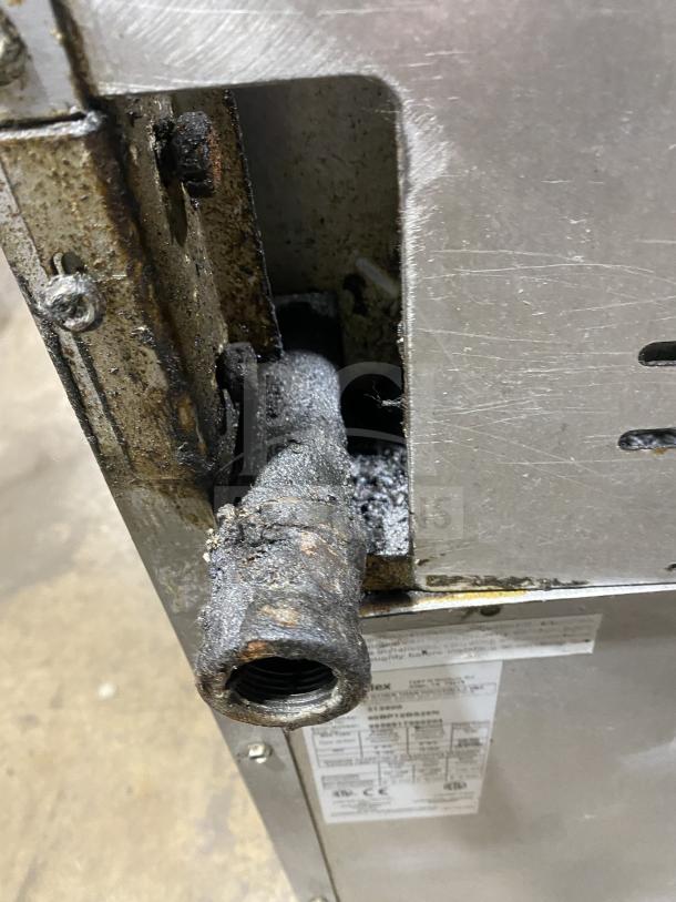 Bakers Pride 60BP10BS26N gas range component. Metal pipe with visible wear and rust, part of commercial oven unit.