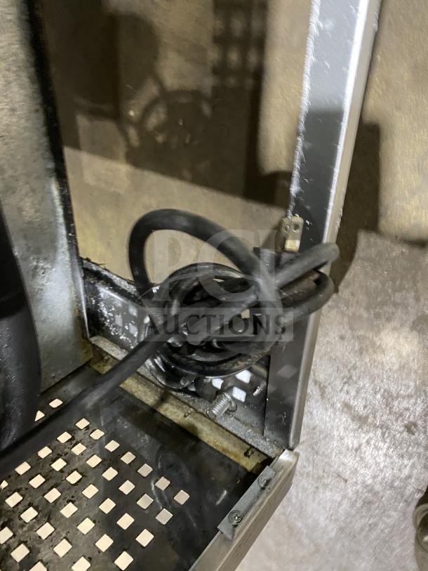 Coiled power cord of a True TUC-72 worktop refrigerator on a metal grid shelf, shown in a storage area.