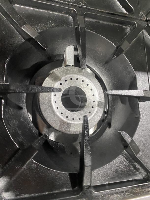 Therma-Tek 6 burner stainless steel gas range detail showing burner and cast iron grate, in good condition.