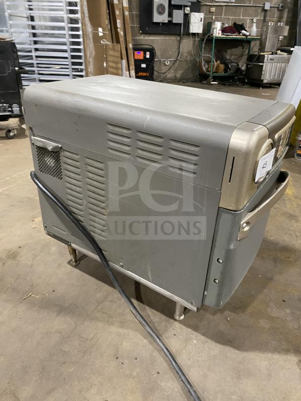 Vintage industrial appliance, gray metal exterior, side vents, heavy-duty plug, moderate wear, attached to rolling cart.