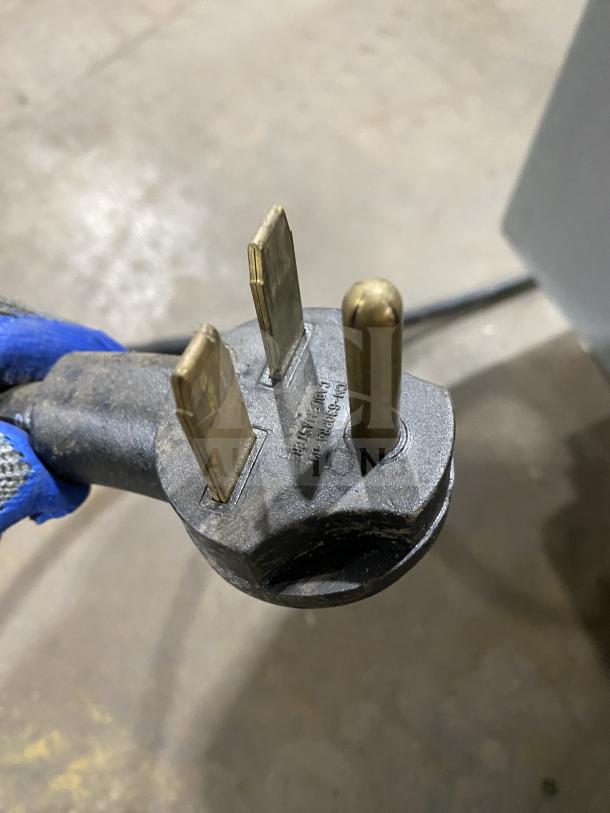 Three-prong electrical plug with visible wear, featuring manufacturer's markings. Suitable for industrial use.