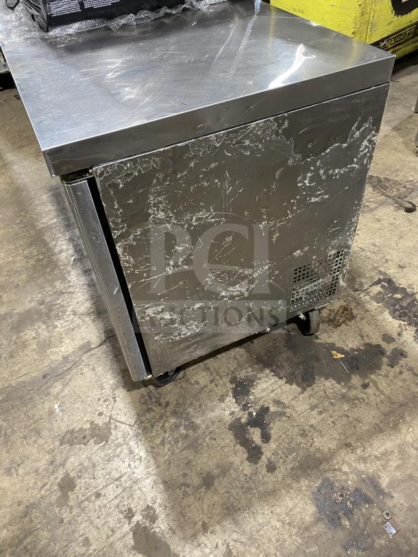 Migali 2-door stainless steel undercounter refrigerator, model C-U60R-HC, on casters, with poly coated wired rack.