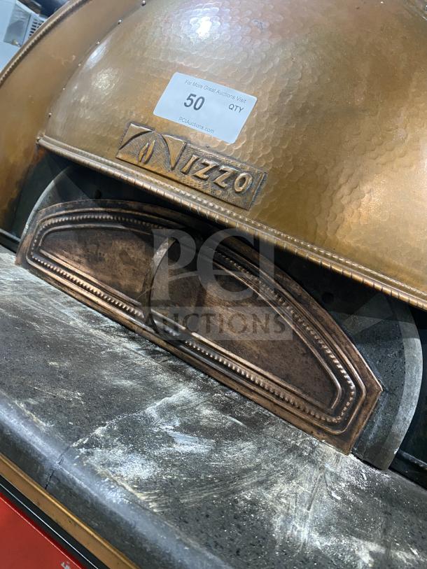 Izzo Forni red dome-style electric pizza oven with wooden paddle; stamped logo on surface, commercial-grade condition.