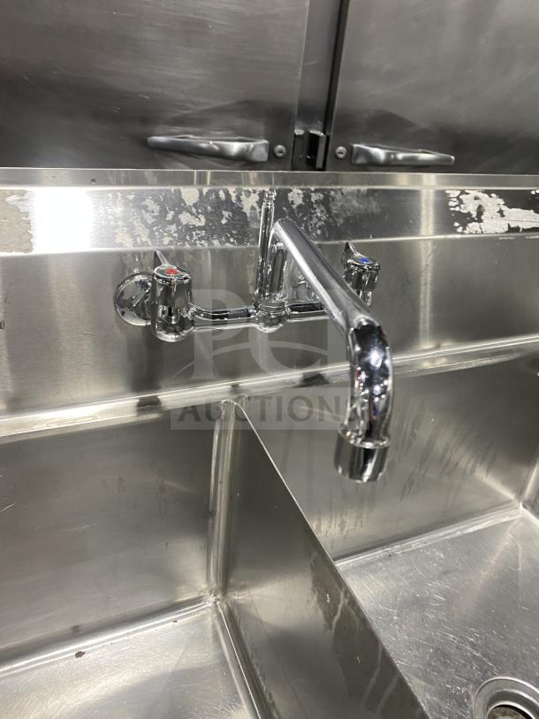 KCS commercial stainless steel 3-compartment sink with faucet, on legs. Visible wear on backsplash, overall good condition.