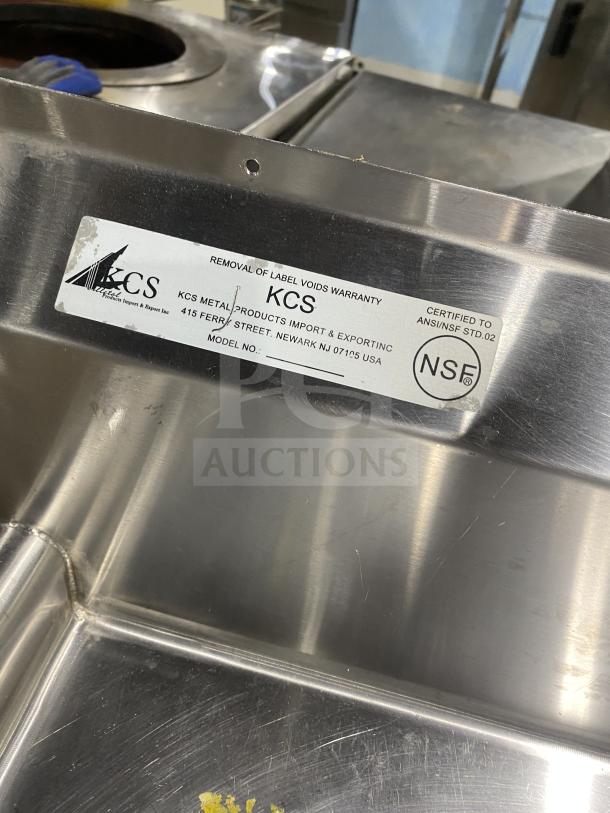 KCS commercial stainless steel 3-compartment sink on legs. Label indicates NSF certification and manufacturer details.
