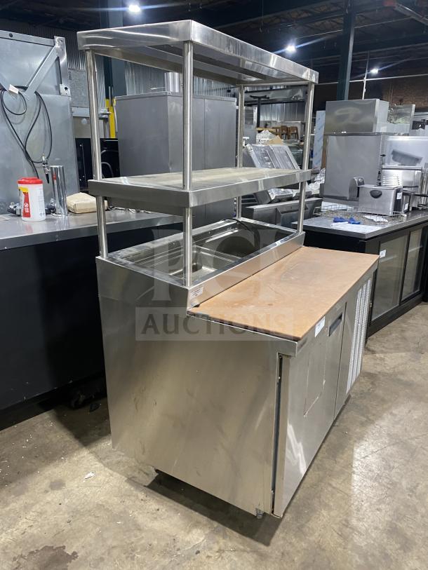 Delfield stainless steel refrigerated prep table with one door, mega top, enclosed storage, and overhead shelves.