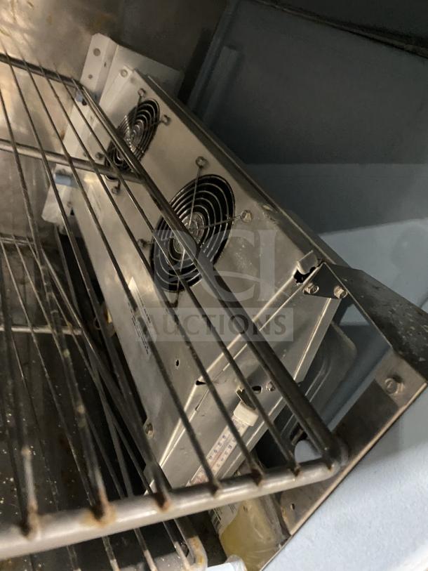 Delfield stainless steel refrigerated prep table with enclosed storage base. Good condition, features overhead shelf.